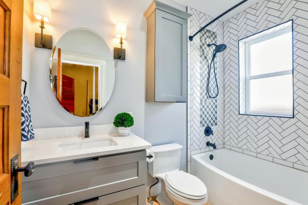Oval Mirror Near Toilet Bowl in a bathroom remodeled by Design Stop