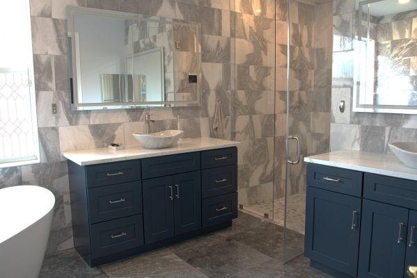 a luxury bathroom, complete with sink, glass shower doors, and blue cabinets